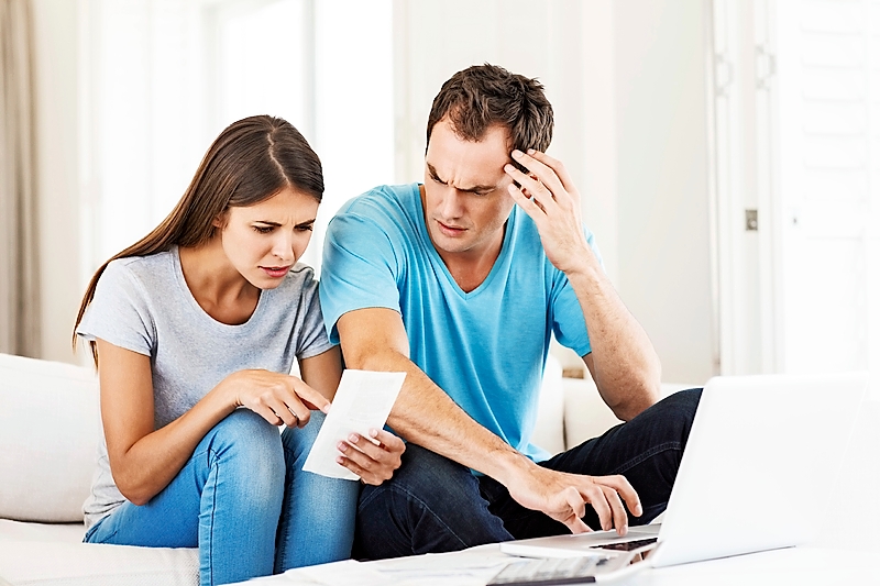 Couple With Laptop Examining Bills