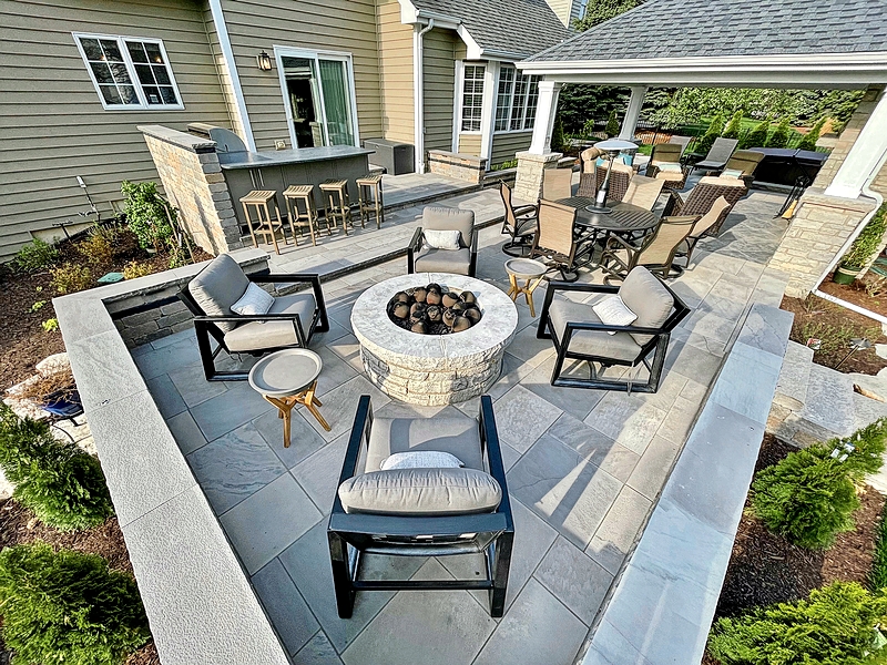 This natural limestone patio in Naperville includes spaces for cooking, eating, and relaxing—mirroring many of the room functions found inside the home. Outdoor cabinetry by Challenger Designs holds cooking tools and serving items for outdoor dinners and parties. And a gas fire pit and outdoor heaters keep the space toasty well into the fall.