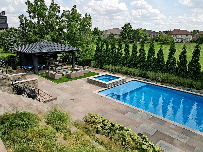 Matt Haber, design director of Western DuPage Landscaping, used artificial turf to carve out an area for relaxing around the fire pit in another Naperville backyard. “Real grass wouldn’t work as well in a high-traffic area like this,” he says. A nearby pavilion, constructed by King’s Court Builders, houses a Ping-Pong table, dining area, and built-in grill. The saltwater pool is by Platinum Pools of Wheeling.