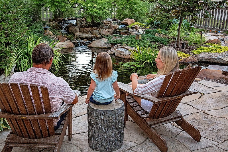 A family relaxing near a backyard pond