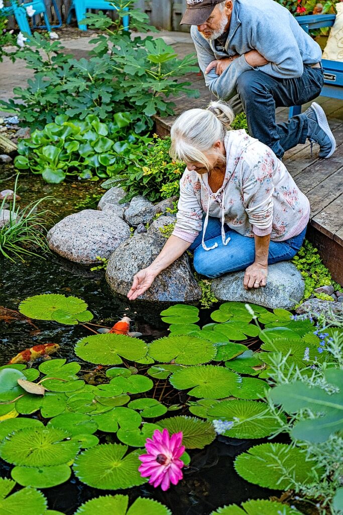A woman feeding koi in a backyard pond