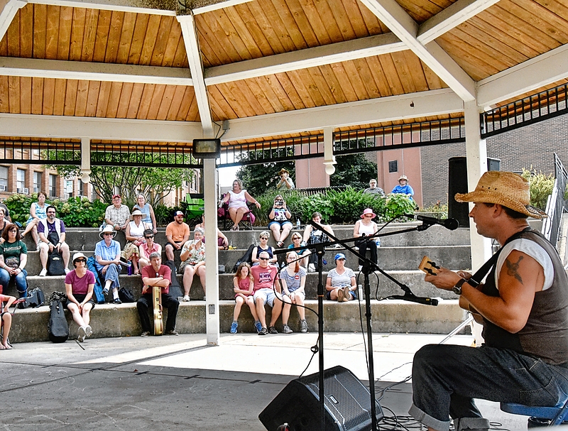 A man performing with a ukelele under a gazebo