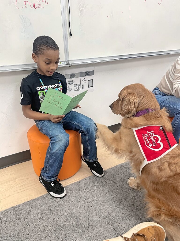 The district is expanding the program to all its 13 elementary schools after finding success with its first therapy dog, Vuolo (pictured, listening to a student).