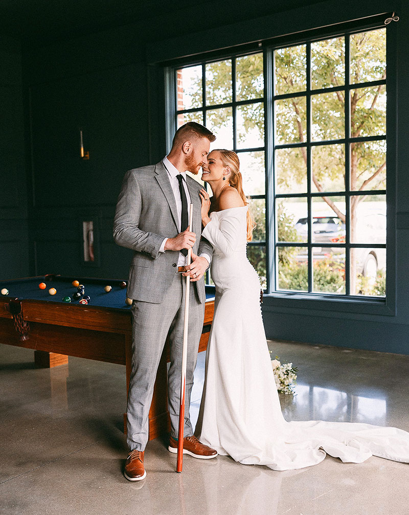 Newlyweds posing by a pool table