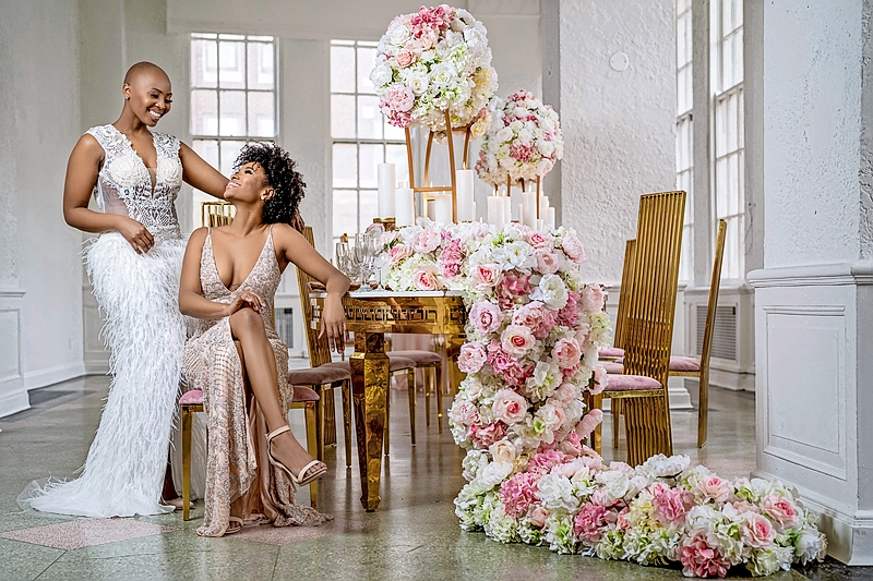 Brides posing by a table lavishly decorated with flowers at Studio 28