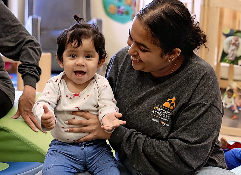 A small child smiling with a caregiver from Metropolitan Family Services DuPage