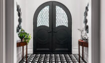 The home’s entryway. The arched door is flanked by matching custom console tables by Studio Gild and two mirrors by Arteriors.