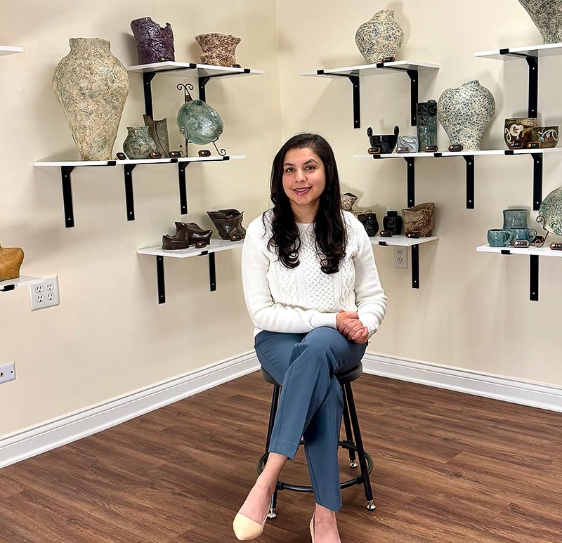 A woman sitting among unique vases at Mud & Easel