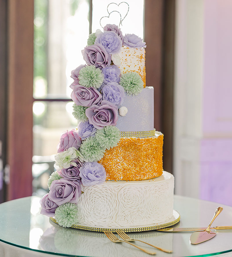 The four-tier wedding cake, decorated with purple and light green flowers