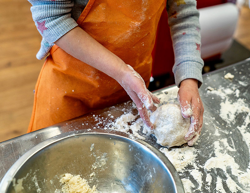 A person in an apron handling dough