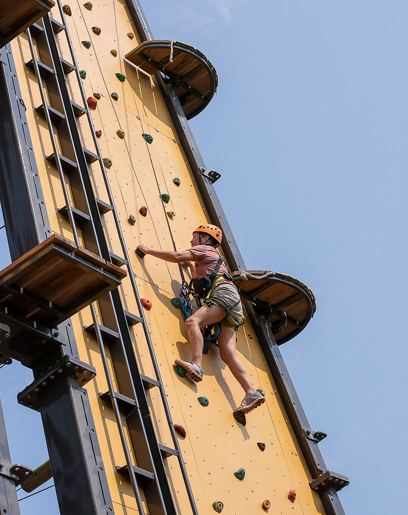 A woman climbing an outdoor vertical wall at The Forge in Lemont