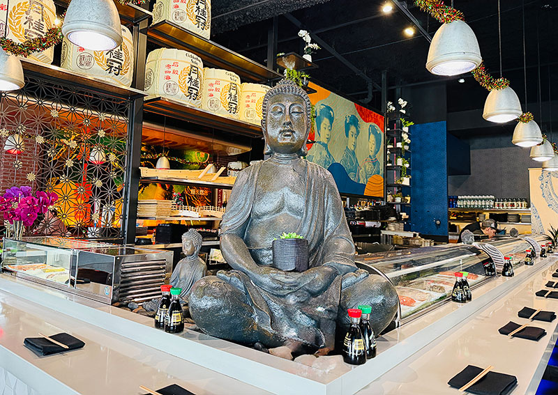 A statue of a person sitting near the sushi bar at Blue Sushi Sake Grill