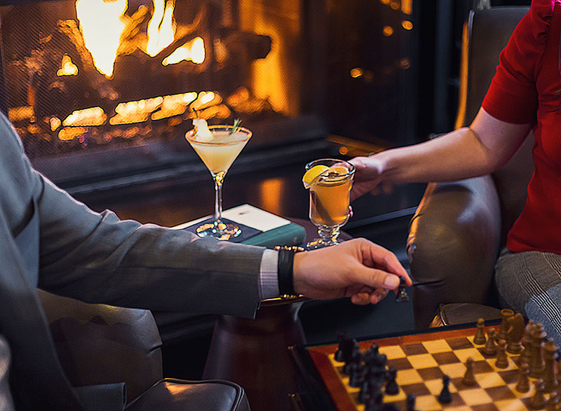 Two people sitting near a chess board with cocktails at The Drake Oak Brook