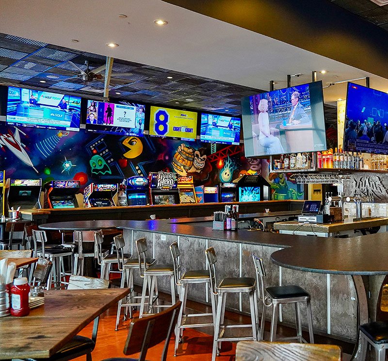 The bar area and video games in the background at Khaos Brewcade & Kitchen