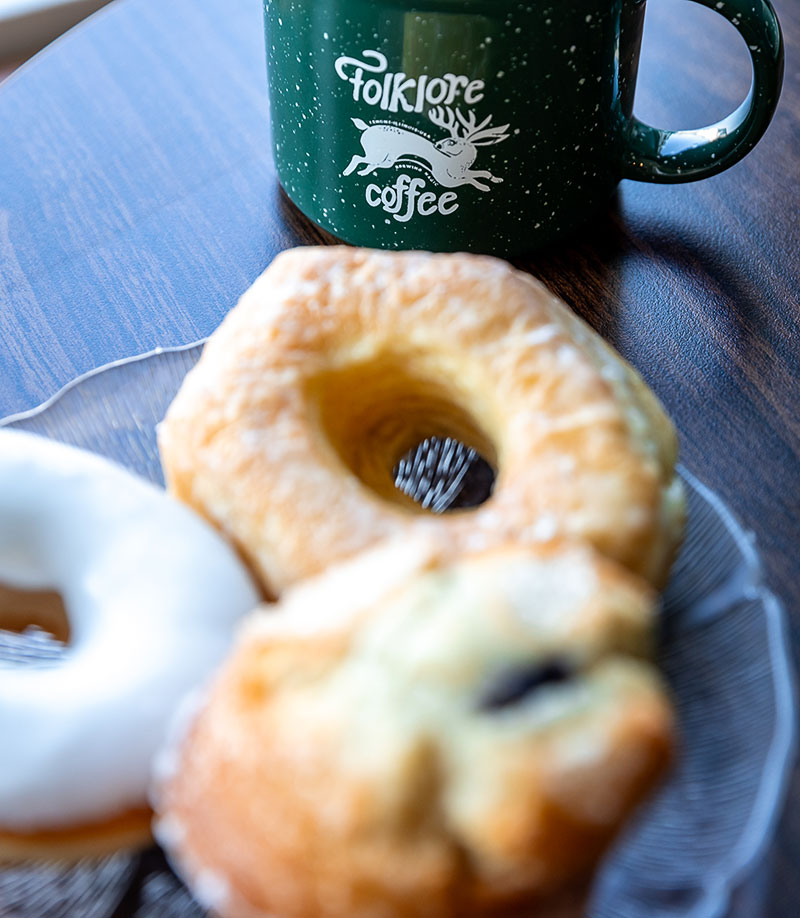 Donuts on a plate in front of a mug of coffee at Folklore Coffee