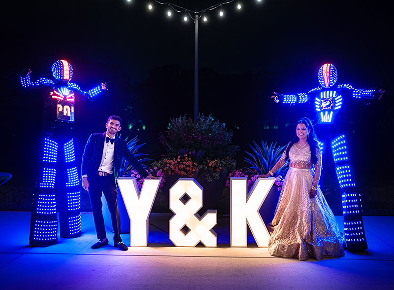 Kabila Ramkumar and Yash Gulabani standing by "Y & K" lights