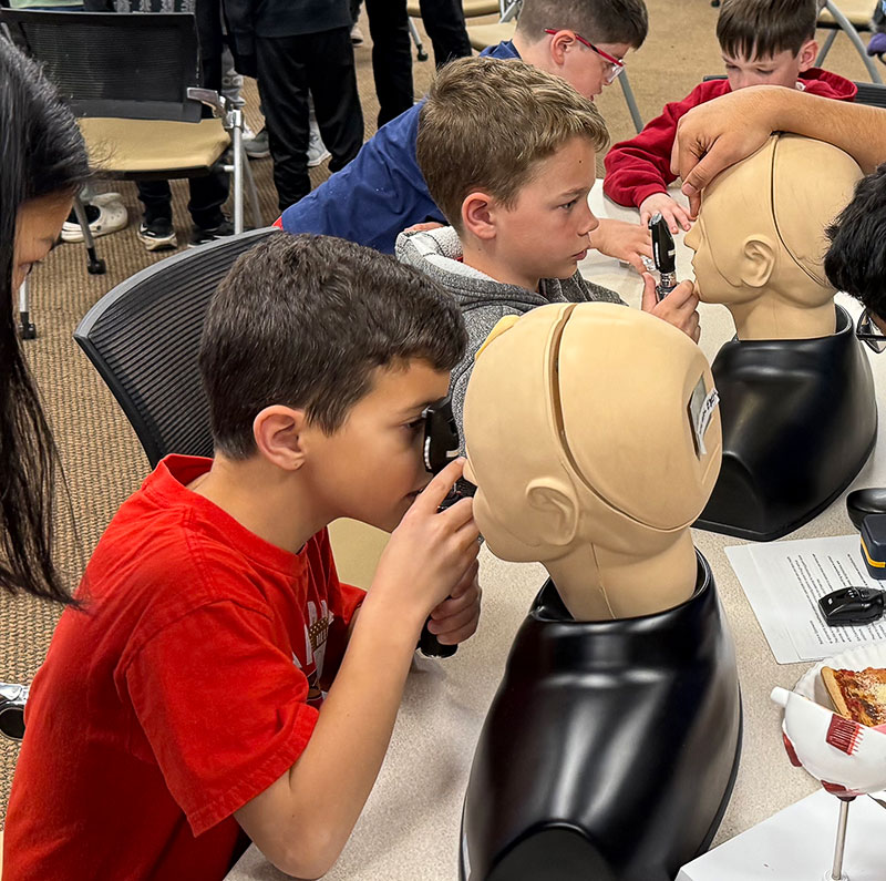 Young boys examining a dummy's eyes at Dr. Rubin’s Mini Medical School