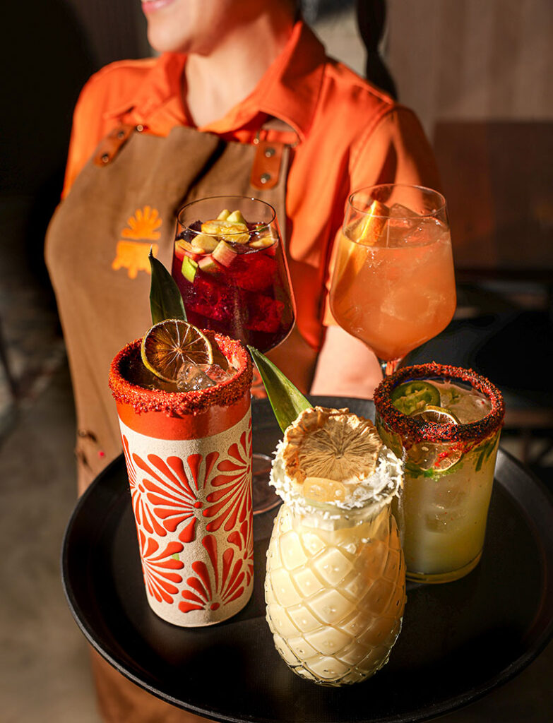 A waitress holding a tray of cocktails at Fonda de Paula