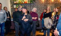 Cindy Hyett holding a microphone while speaking to a group of people at Clarify Kitchen