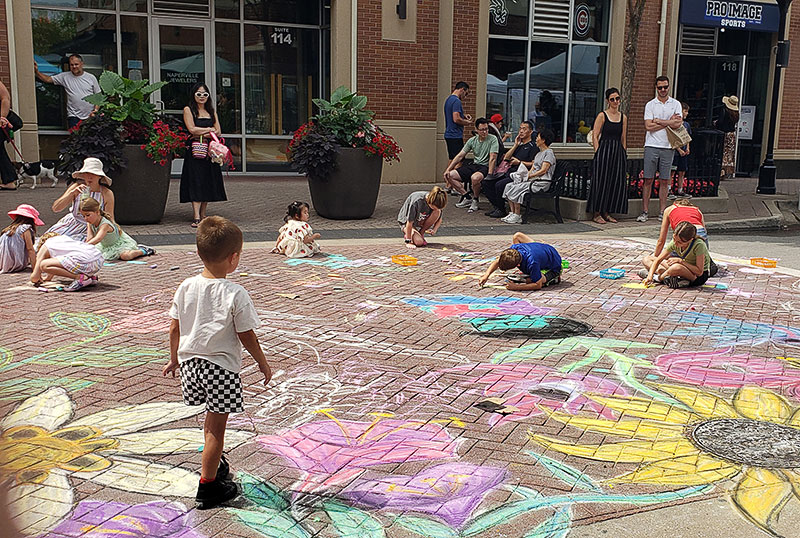 Kids making chalk drawings on the ground at the Water Street Fine Art & Fine Craft Fair in Naperville