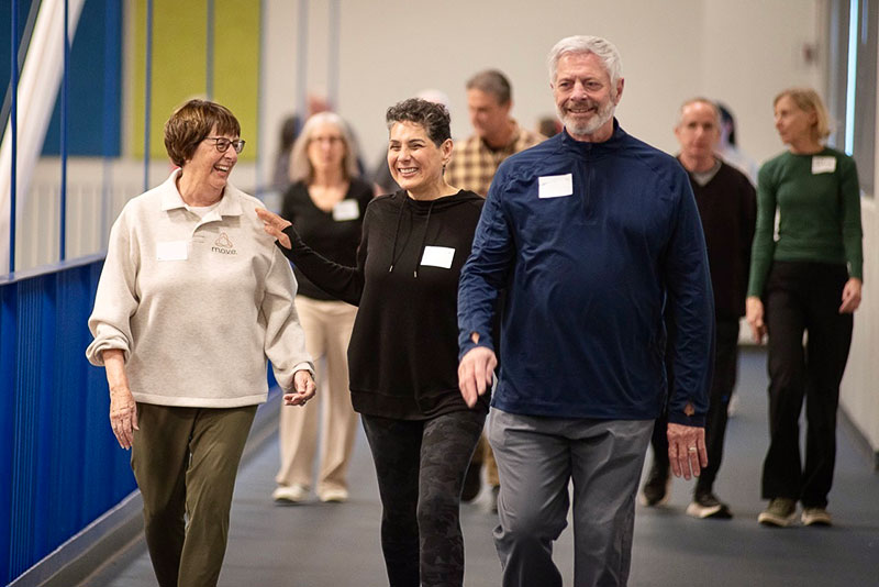 A group of smiling seniors walking down a hallway